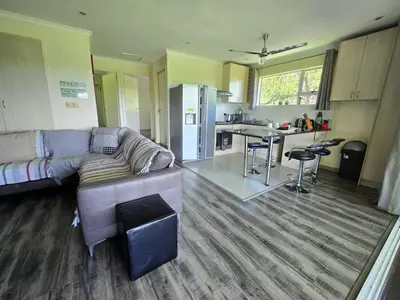 a living room with a couch and a kitchen at Hills and Dales Accommodation in Lanseria