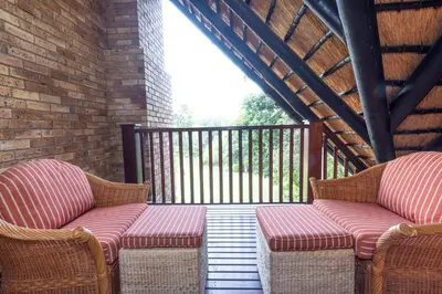 two wicker chairs sitting on a porch with a railing at Legend Safaris 257A - in Kruger Park Lodge in Hazyview