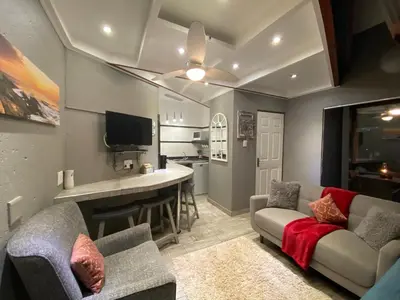 a living room with a couch and a kitchen at Boomhuisie in Komatipoort