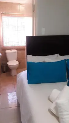 a bedroom with a bed with a blue pillow on it at Valley Guest House in Pretoria