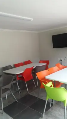 a room with tables and chairs and a flat screen tv at Valley Guest House in Pretoria