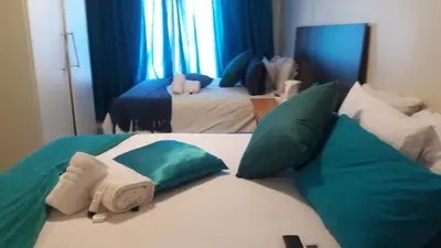 a bedroom with two beds with green and white pillows at Valley Guest House in Pretoria