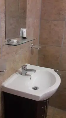 a white sink in a bathroom with a mirror at Valley Guest House in Pretoria
