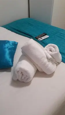 a white towel on a bed with a remote control at Valley Guest House in Pretoria