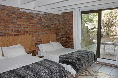 two beds in a room with a brick wall at Jabula Kruger Safari Lodge in Marloth Park