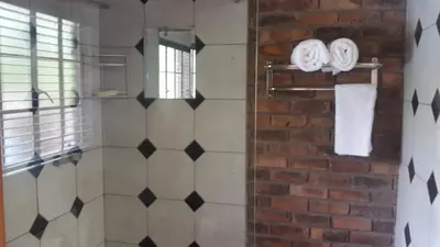 a bathroom with white towels and a brick wall at Jabula Kruger Safari Lodge in Marloth Park