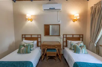two beds in a room with a table and a mirror at Kruger Park Lodge Unit No. 543 in Hazyview