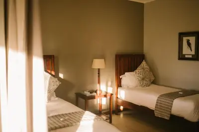 a hotel room with two beds and a lamp at Hamiltons Lodge & Restaurant in Malelane