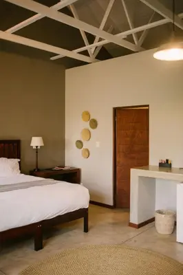 a bedroom with a bed and a wooden door at Hamiltons Lodge & Restaurant in Malelane