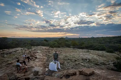 a group of people sitting at a table on a mountain at Rukiya Safari Camp in Hoedspruit