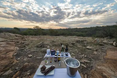 a table with bottles of wine on top of a hill at Rukiya Safari Camp in Hoedspruit