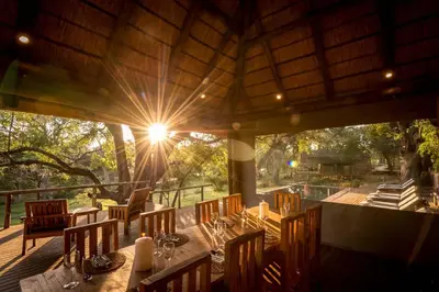 a restaurant with a table and chairs on a deck at Rukiya Safari Camp in Hoedspruit