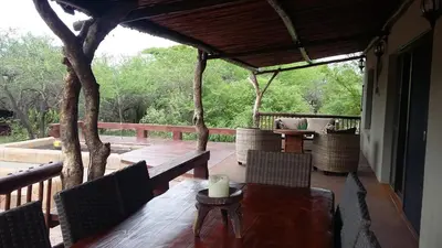 a porch with a wooden table and chairs on a deck at Marloth Kruger Whispering Ants in Marloth Park