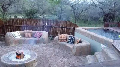 a patio with two couches and a fire pit next to a pool at Marloth Kruger Whispering Ants in Marloth Park
