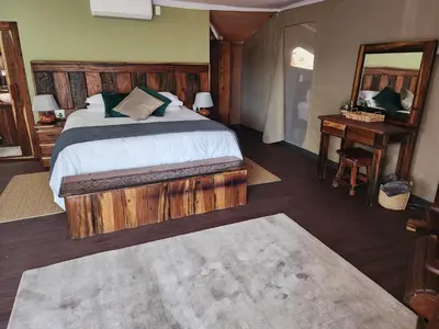 a bedroom with a large bed and a mirror at Crimson Bush Lodge in Klipdrift