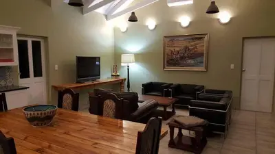 a living room with couches and a table and a television at Crimson Bush Lodge in Klipdrift
