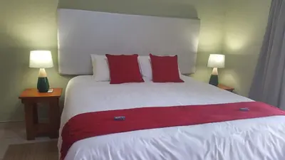 a bedroom with a large white bed with red pillows at Crimson Bush Lodge in Klipdrift