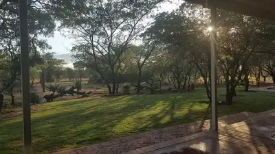 a view of a park with trees and grass at Crimson Bush Lodge in Klipdrift