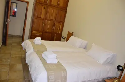 a bedroom with two beds with white sheets and towels at Stoep At Steenbok Self Catering in Komatipoort