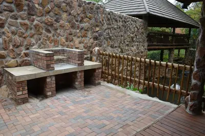 a stone wall with a bench on a brick patio at Stoep At Steenbok Self Catering in Komatipoort