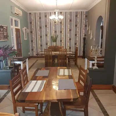 a dining room with wooden tables and chairs at Stoep At Steenbok Self Catering in Komatipoort