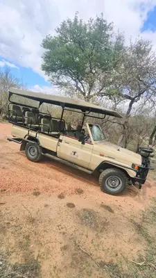 a beige jeep parked in a field with a safari at The Baobab Bush Lodge and Villa in Hoedspruit