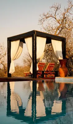 a gazebo with chairs next to a swimming pool at The Baobab Bush Lodge and Villa in Hoedspruit