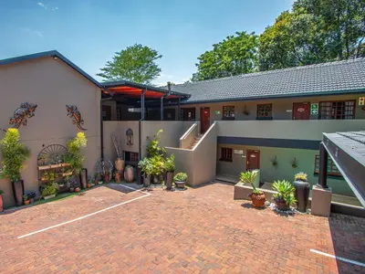 a building with a brick courtyard with potted plants at Casa Albergo Corporate Guest House in Pretoria