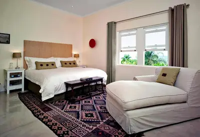 a bedroom with a bed and a couch and a chair at umSisi House in White River