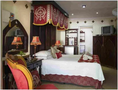 a bedroom with a large bed and a mirror at De Ark Guest House in Lydenburg