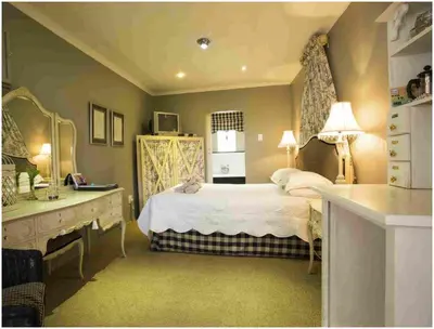 a bedroom with a bed and a vanity and a sink at De Ark Guest House in Lydenburg