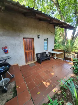 a patio with a bench and a table in front of a house at Softwaters Guesthouse Cottages in Louis Trichardt