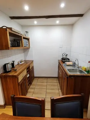 a small kitchen with wooden cabinets and a sink at Softwaters Guesthouse Cottages in Louis Trichardt