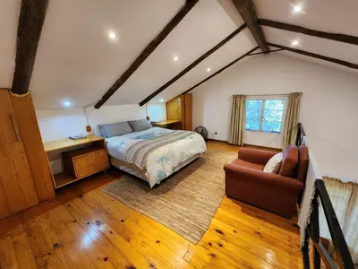 a bedroom with a bed and a desk and a couch at Softwaters Guesthouse Cottages in Louis Trichardt