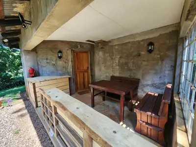 a porch with a wooden table and a bench at Softwaters Guesthouse Cottages in Louis Trichardt
