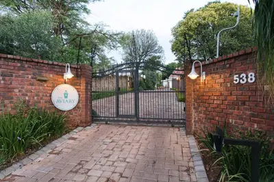 a brick driveway with a gate with a sign on it at The Aviary in Pretoria