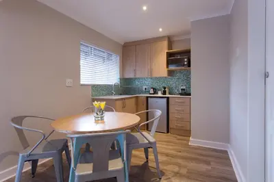 a small kitchen with a wooden table and chairs at The Aviary in Pretoria