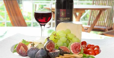 a glass of wine sitting next to a plate of fruit at The Lakes Boutique Lodge in Pretoria