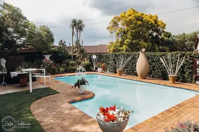 a swimming pool in a yard with plants and a table at Dara Guest House in Trichardt