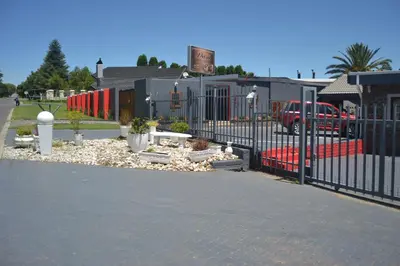 a black fence in front of a building with plants at Dara Guest House in Trichardt