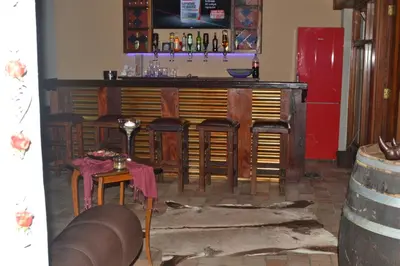 a bar with wooden bar stools in a room at Dara Guest House in Trichardt