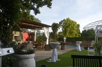 a patio with white tables and chairs in a yard at Dara Guest House in Trichardt