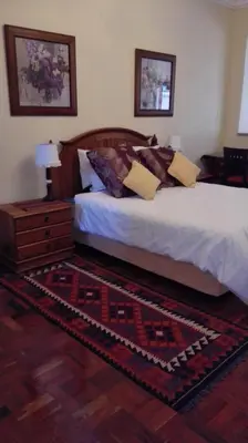 a bedroom with a bed and a dresser and a rug at House Rossini in Pretoria
