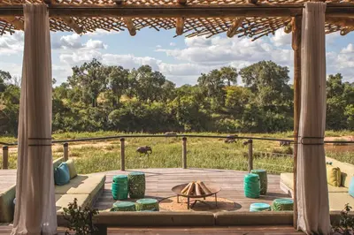 a deck with a table and chairs and a view of a field at Lion Sands Narina Lodge in Sabi Sand Game Reserve