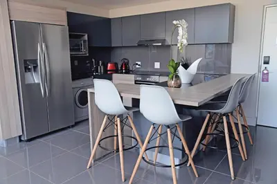 a kitchen with a wooden table and white chairs at The Capital Menlyn Maine in Pretoria
