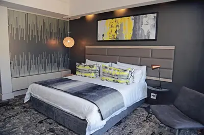 a bedroom with a large bed and a chair at The Capital Menlyn Maine in Pretoria