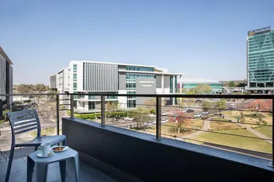 a balcony with a chair and a view of a city at The Capital Menlyn Maine in Pretoria