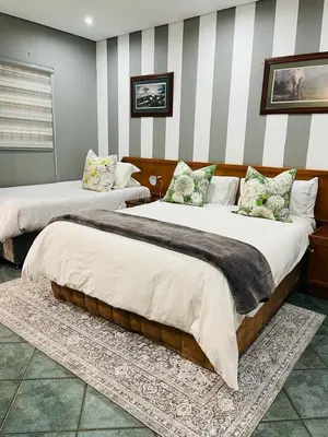 two large beds in a room with striped walls at Pari Guest House in Middelburg