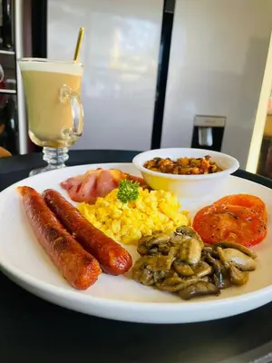 a plate of food with sausage scrambled eggs and mushrooms at Pari Guest House in Middelburg