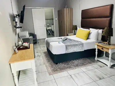a bedroom with a bed and a desk and a bed sidx sidx sidx at Pari Guest House in Middelburg